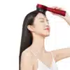 Woman using electric scalp massage comb on her hairline